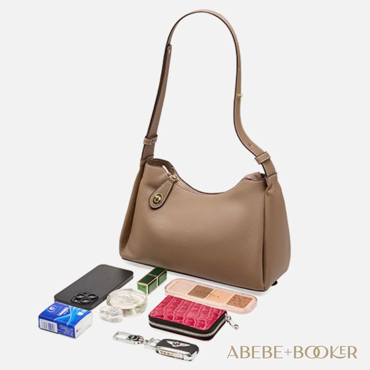 Trapezoid Leather Crossbody Handbag in brown with accessories displayed around it. Scratch-resistant genuine leather