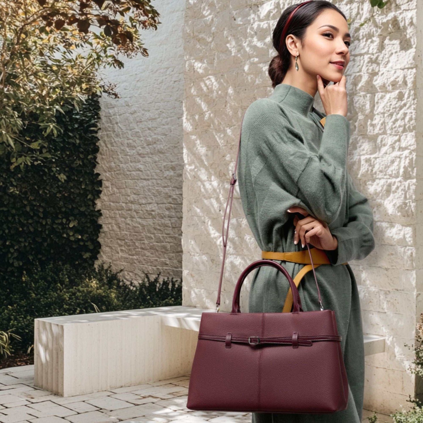 Woman carrying a dark red leather briefcase bag outdoors.