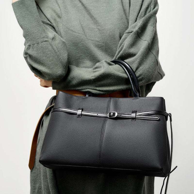 Women's genuine leather briefcase bag in black, featuring a chic belt buckle detail, held