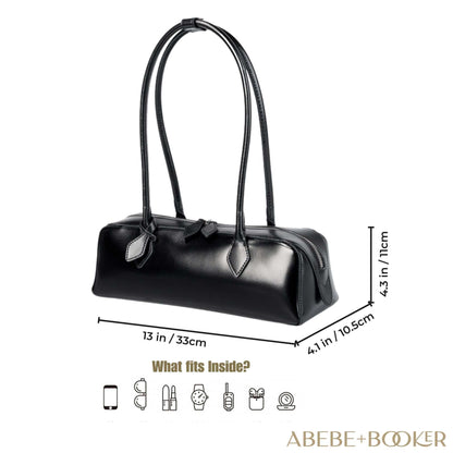 Black leather baguette bag with curved silhouette, rolled leather handles, and double zipper; size 13" x 4.3" x 4.1".