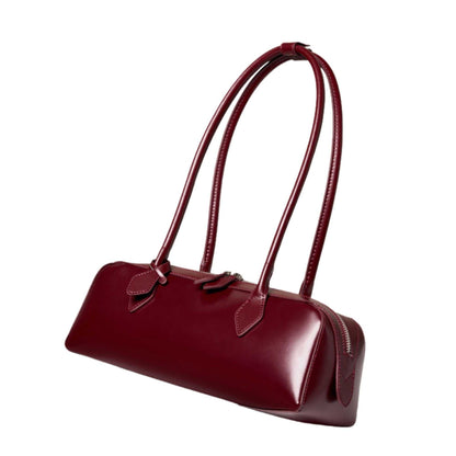 Sleek leather baguette bag with rolled handles and modern design.