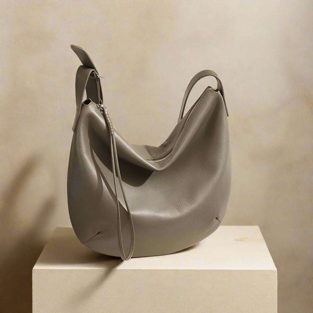 Slouchy Crossbody Bag in leather with adjustable strap displayed on pedestal.