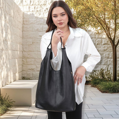 Woman carrying black slouchy leather hobo bag outdoors.