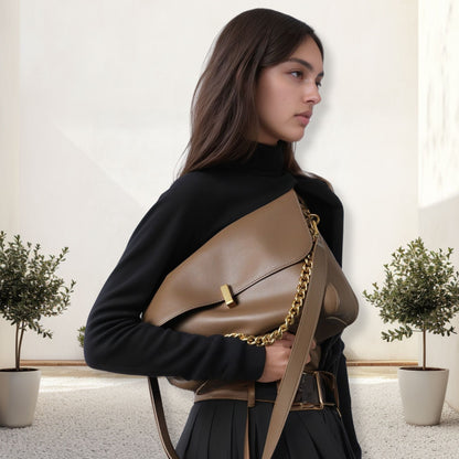 Woman holding a stylish small messenger purse in genuine leather with a chain strap, showcasing versatility and