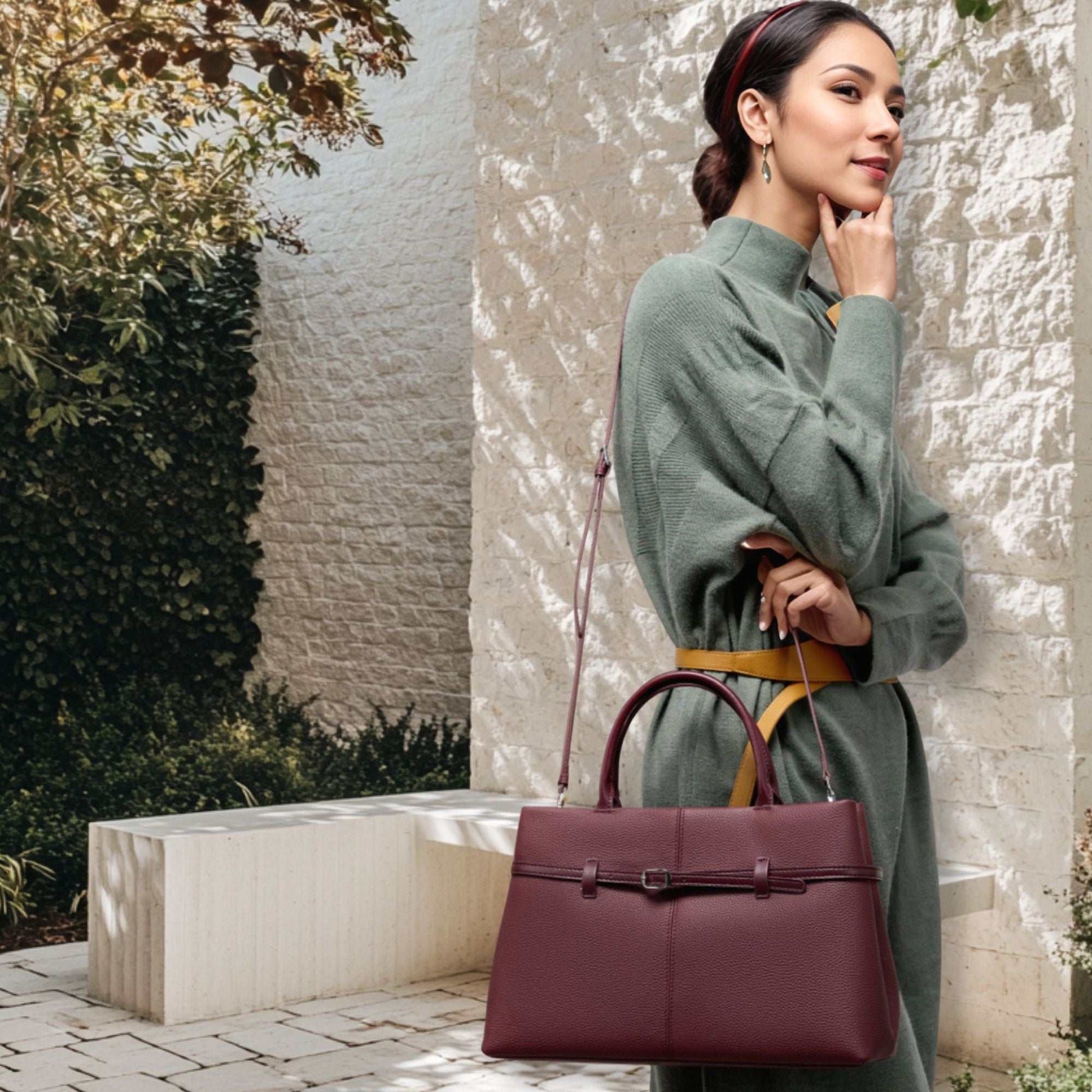 Woman carrying a dark red leather briefcase bag outdoors.