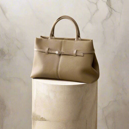 Women's leather briefcase bag in elegant design, displayed on a stylish pedestal.
