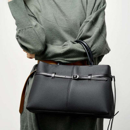 Women's genuine leather briefcase bag in black, featuring a chic belt buckle detail, held